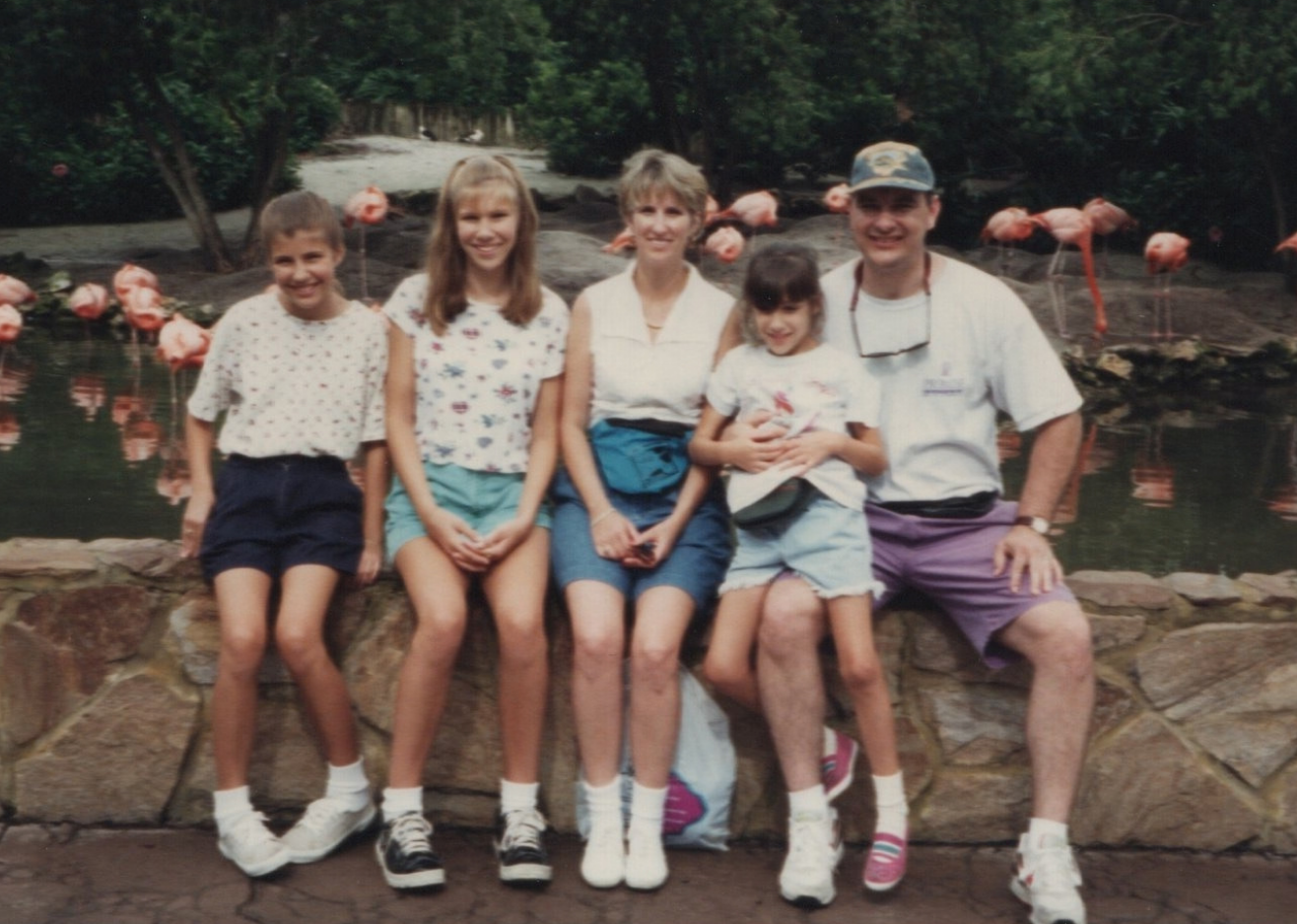 Mom, dad, me, Kara, Kanon, in front of wading flamingos in a pond with a background of trees.